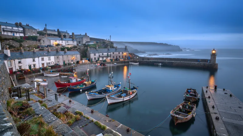 Landscape photograph of a fishing village built on terraced cliffs above a small harbor at blue hour